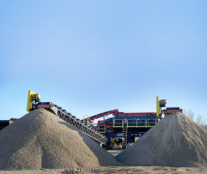 Sandvik UK373 electrically driven wheel crusher in operation with two stock piles in front of it (photo)