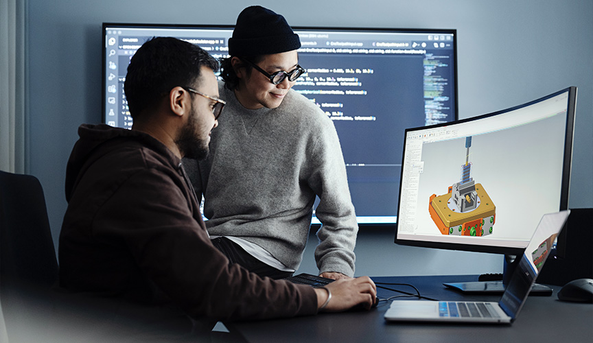 Två män tittar på en skärm som visar en CAD-modell av en komponent. (foto)