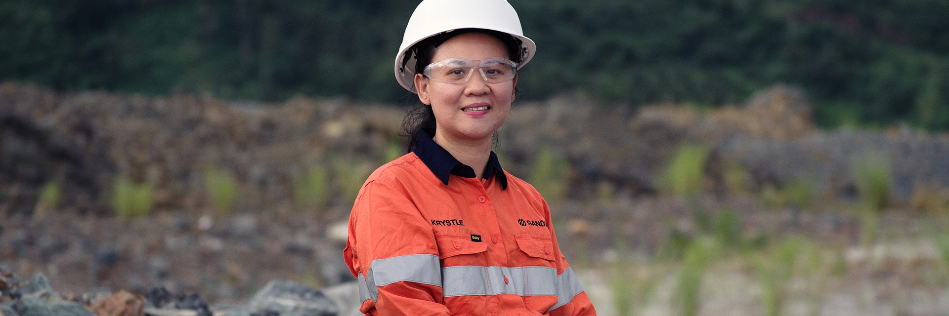 En kvinna i hjälm och skyddsutrustning sitter på en sten. (foto)